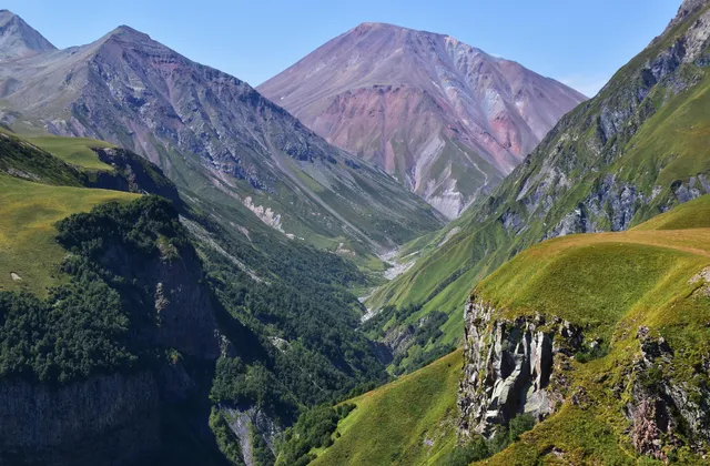 A green valley cutting through the rugged Caucasus mountains in Georgia