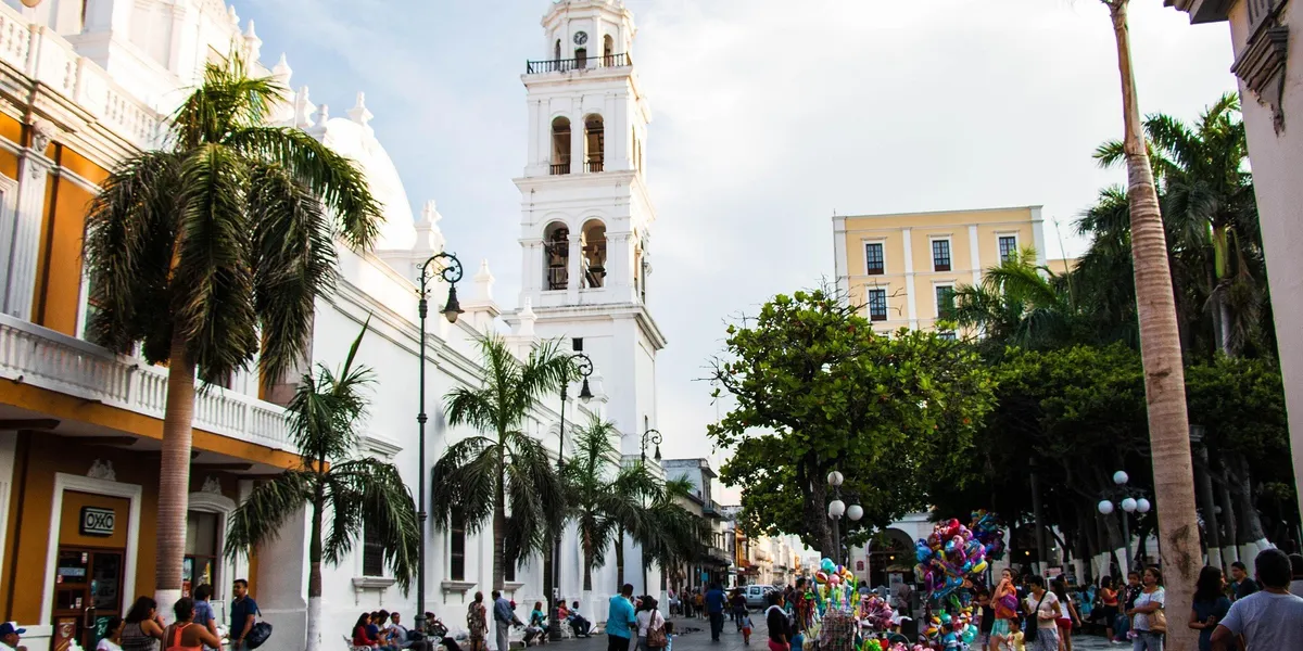 A palm-lined plaza in front of the white cathedral bell tower in Veracruz, Mexico