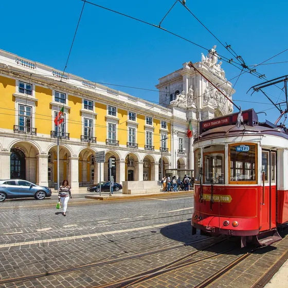 A vintage red tram passing the Praça do Comércio in Lisbon, Portugal