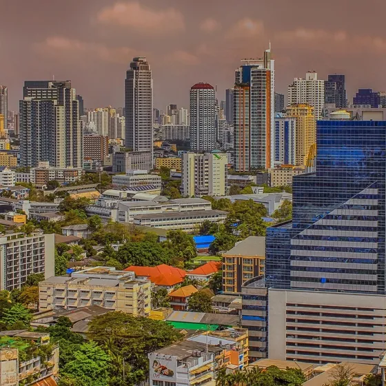 The Bangkok skyline of high-rises and glass towers under a dusky sky